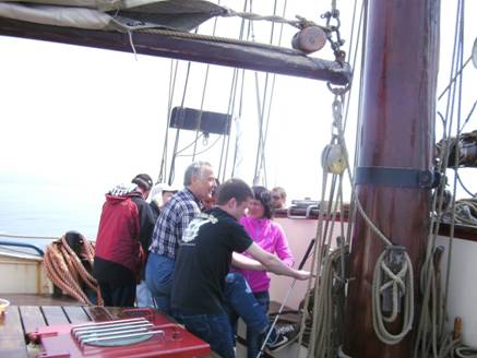 Foto: Segelsetzen des Hauptsegels. Man sieht die Sehleute: Anne, Georg, Boris, Stephan, Oli und Norbert.