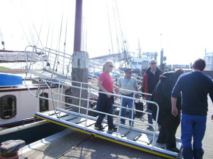 Foto: Landgang auf Norderney. Zu sehen sind einige Teilnehmer die über eine gut gesicherte Stahlrailing das Segelboot verlassen. Die Laune ist gut und das Wetter ist ...... noch besser!
